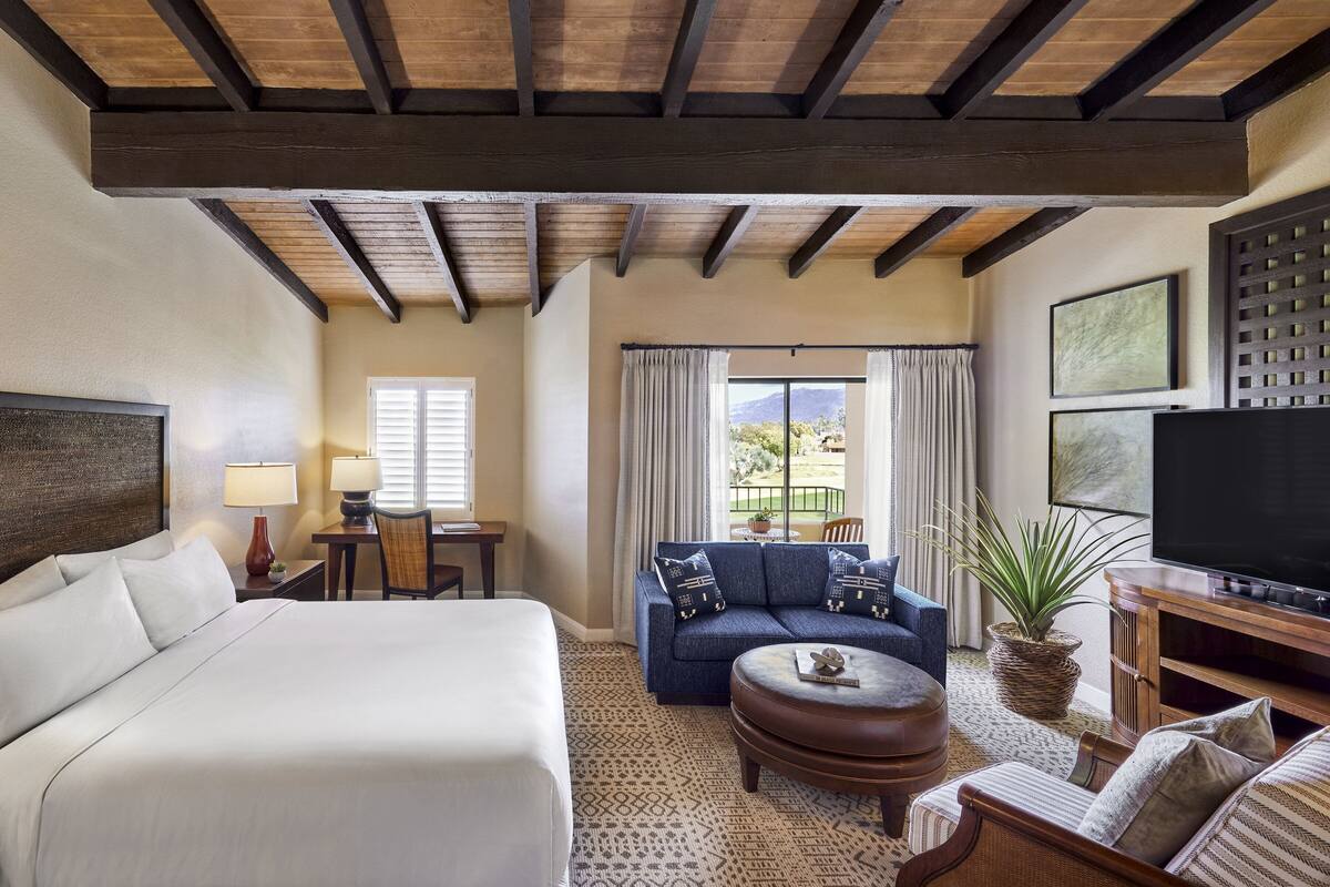 Une chambre d’hôtel avec un grand lit, un canapé, une télévision et un coin repas comprenant une table et des chaises.