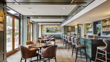 A restaurant with a bar area, wooden tables, and chairs.