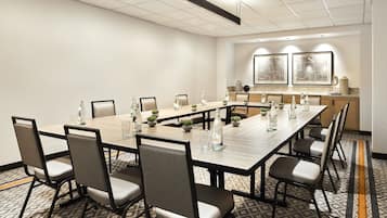 A conference room with a long table, chairs, and a kitchen area in the background.