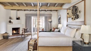 A spacious bedroom with a large bed, a fireplace, a wooden ceiling, and a view of the outdoors. - Omni Tucson National Resort & Spa (Tucson)