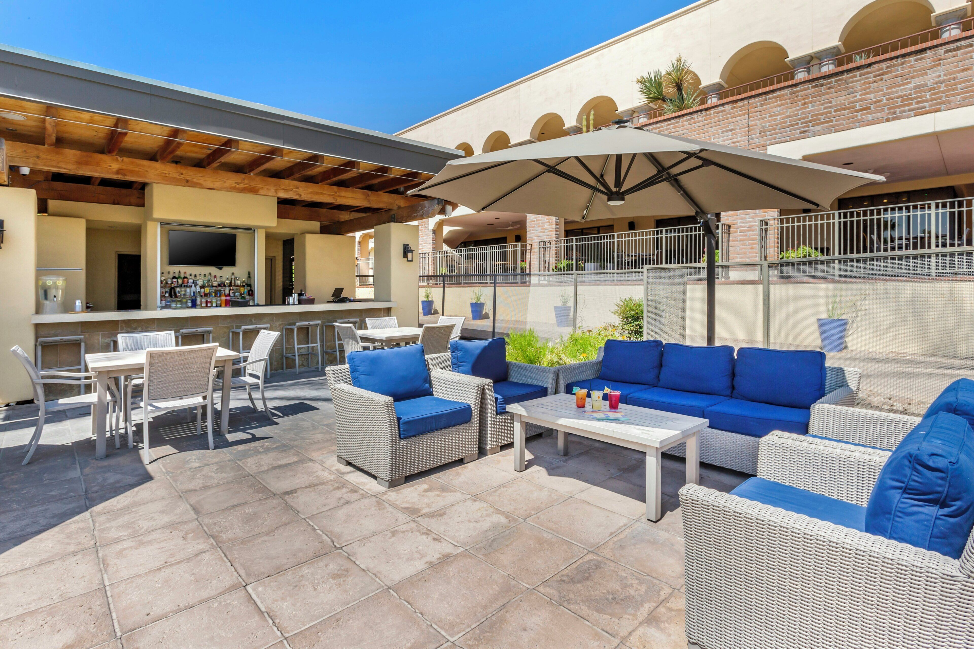 An outdoor patio area with seating, a bar, and a TV screen.