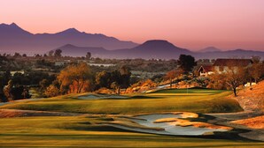 A golf course with a clubhouse, sand bunkers, and distant mountains. - Omni Tucson National Resort & Spa (Tucson)