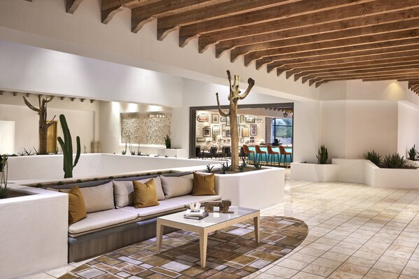 A modern interior with a white sofa, a coffee table, and a wooden ceiling.