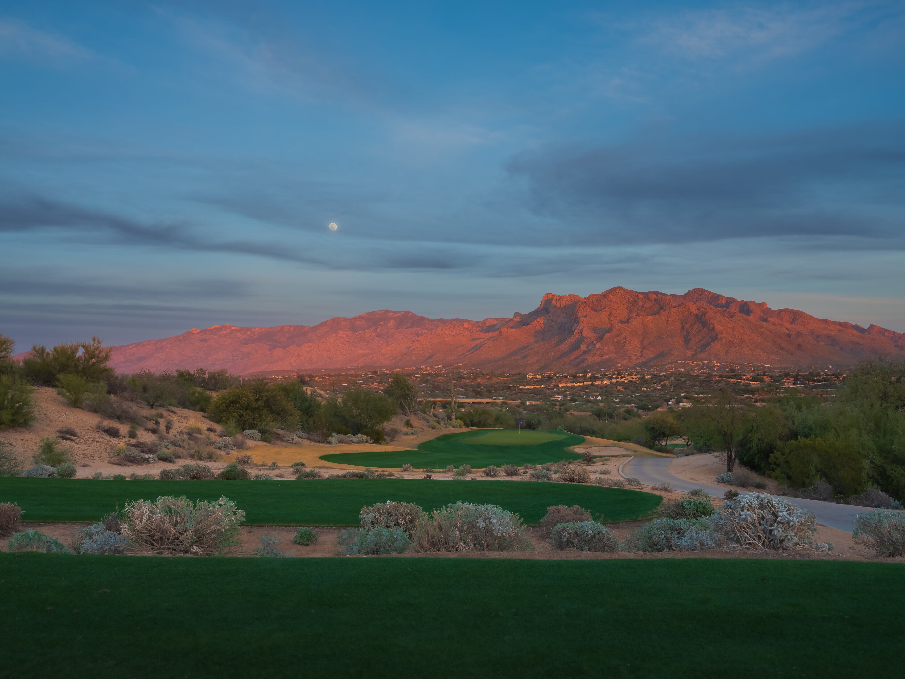 A golf course with a mountain backdrop and a clear sky.