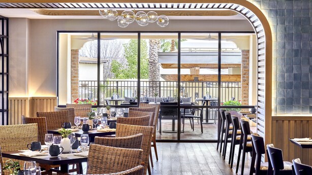A restaurant with wicker chairs, tables set for dining, and a view of the outdoors. - Omni Tucson National Resort & Spa (Tucson)