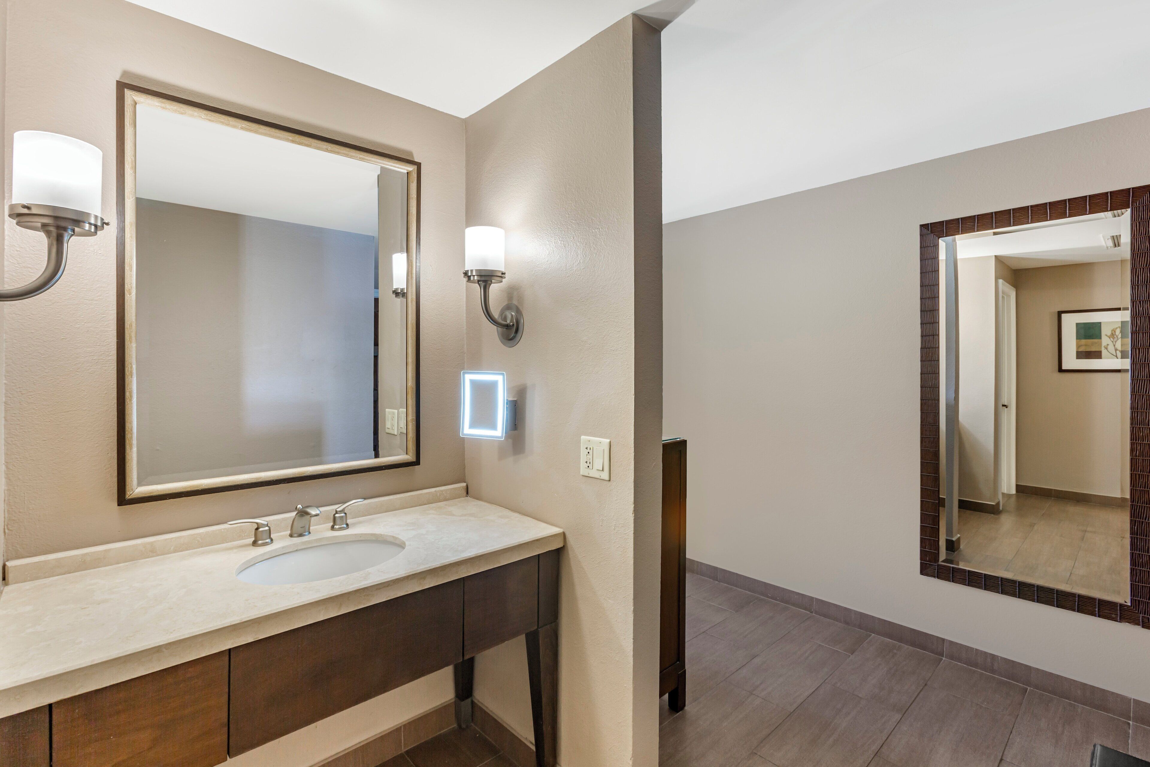 Une salle de bain moderne avec un grand miroir, un lavabo et deux appliques murales.