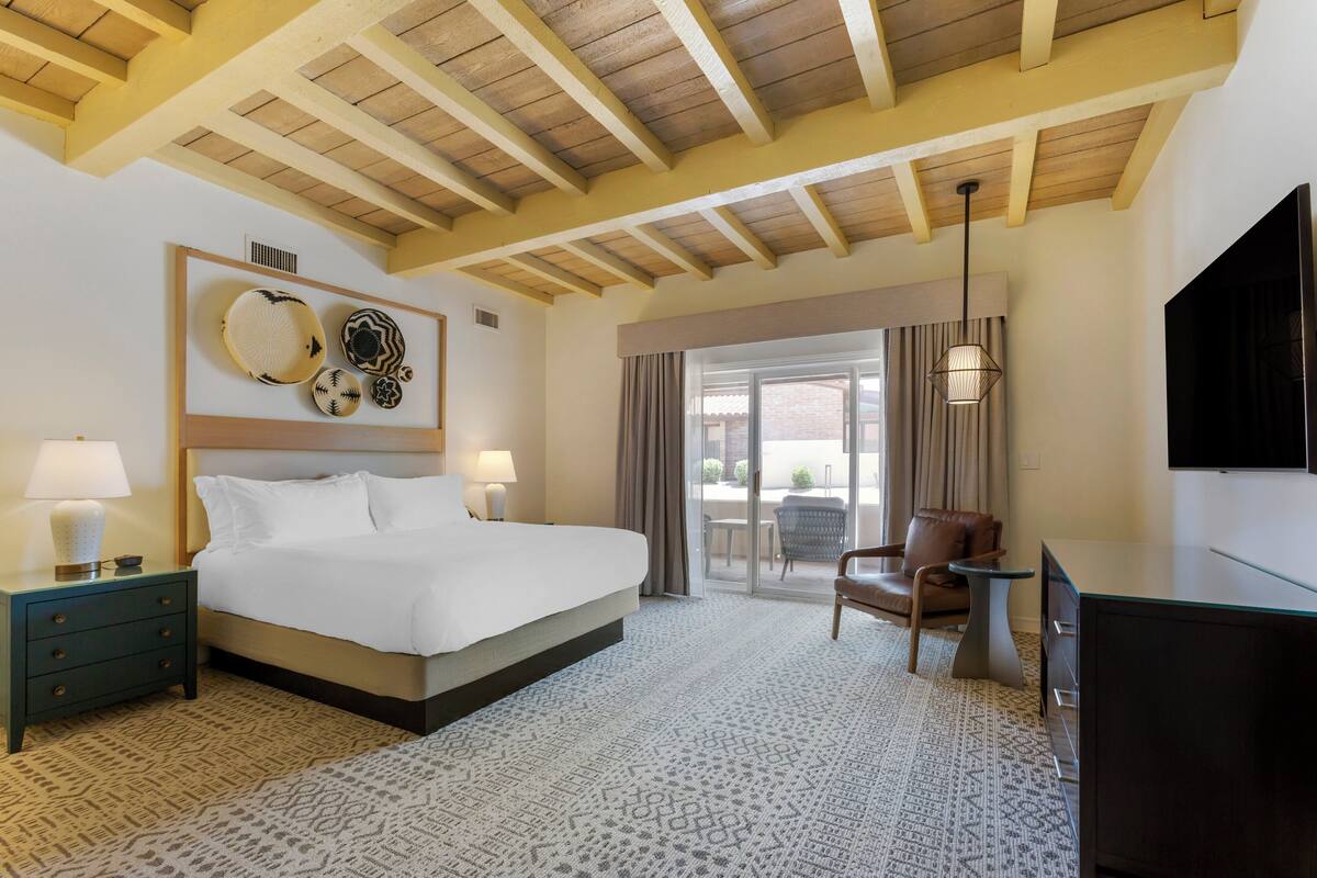 Une chambre d’hôtel avec un grand lit, un bureau, une chaise et un téléviseur.