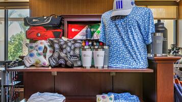 Exhibición de artículos de viaje que incluyen bolsos, una gorra y botellas de agua con el logotipo 'Tucson National'.