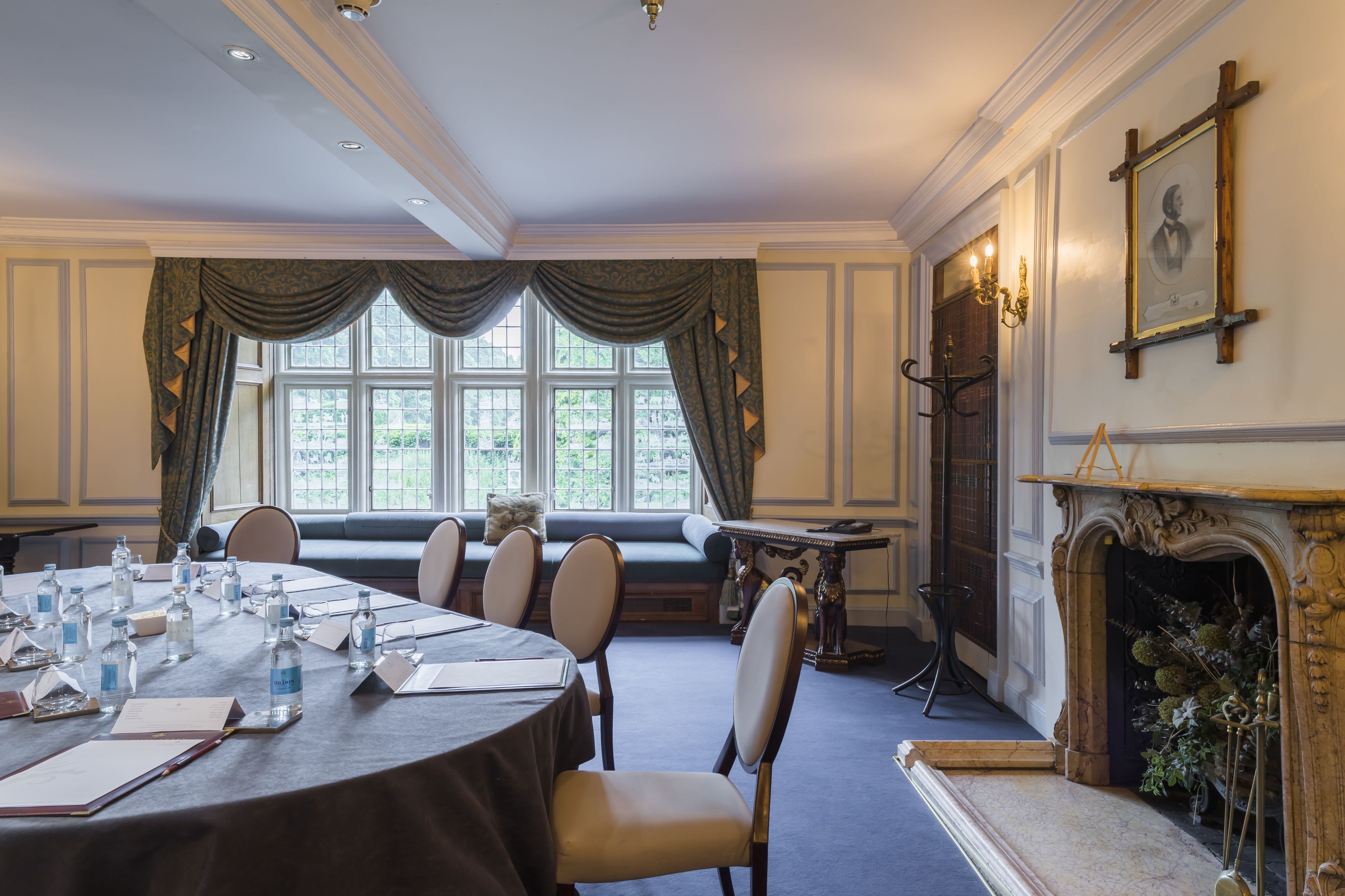 A formal dining room with a round table, chairs, and a fireplace.