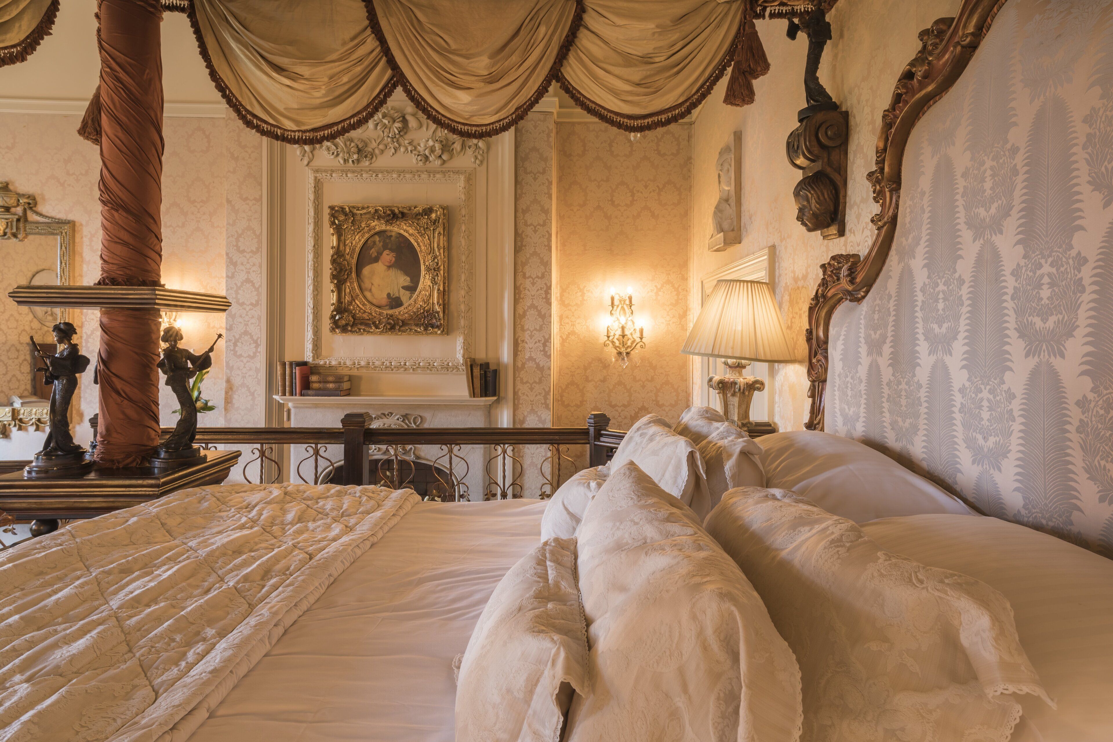 Un dormitorio lujoso con una cama ornamentada, un candelabro y una chimenea.