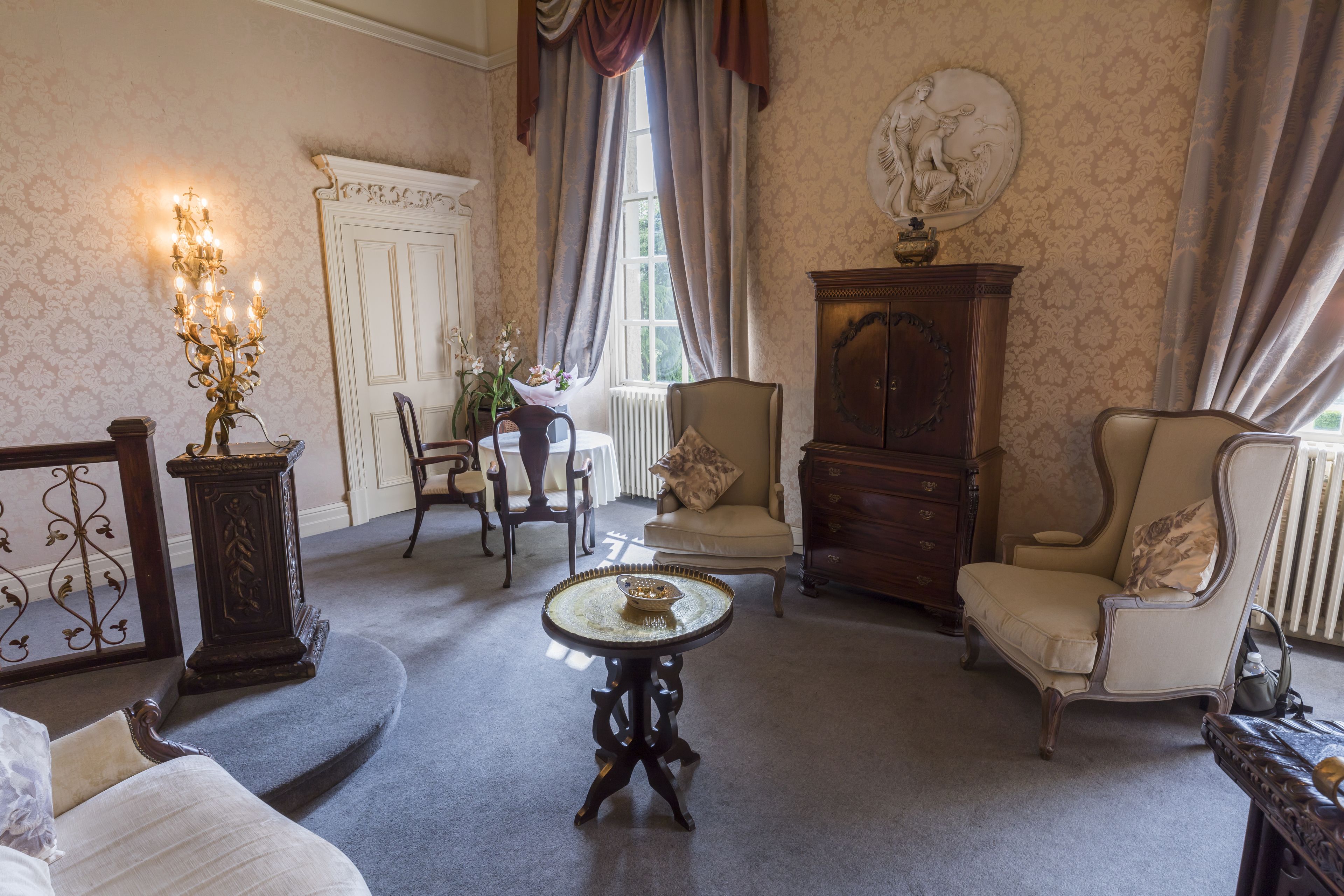 A room with a round table, a sofa, a cabinet, and a chair.