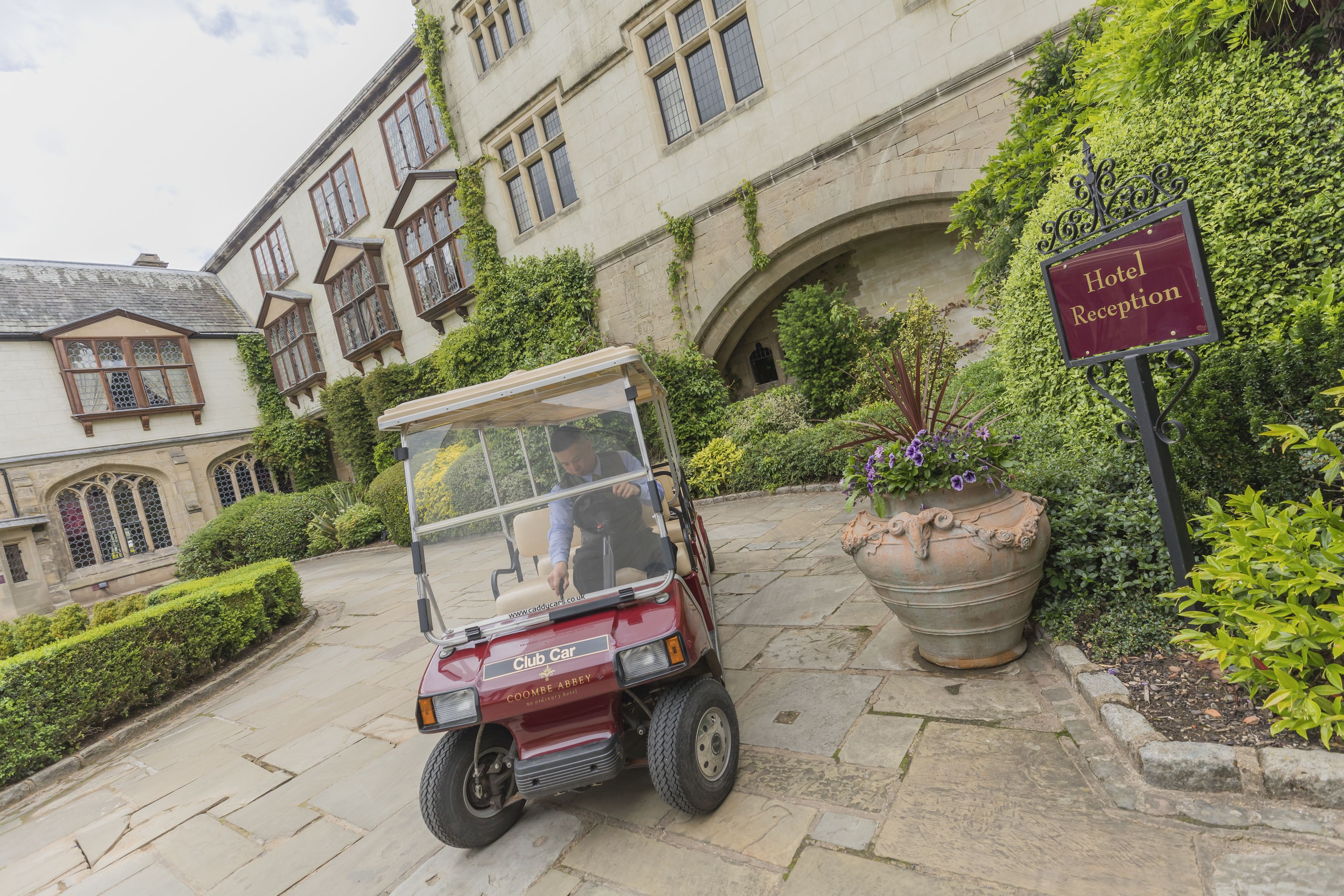 A Club Car parked in front of a historic building with a 'Hotel Reception' sign.