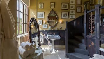 A bathroom with a sink, mirror, and towel rack. There are framed pictures on the wall and a staircase leading to another room.