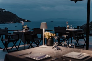 A table set for dining with a view of the sea and hills in the background.