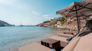 Een privéstrand, ligstoelen aan het strand, parasols, strandlakens