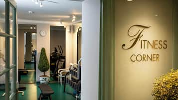 Interior de academia com equipamentos de exercício, um relógio e um aviso com a inscrição 'Fitness Corner'.