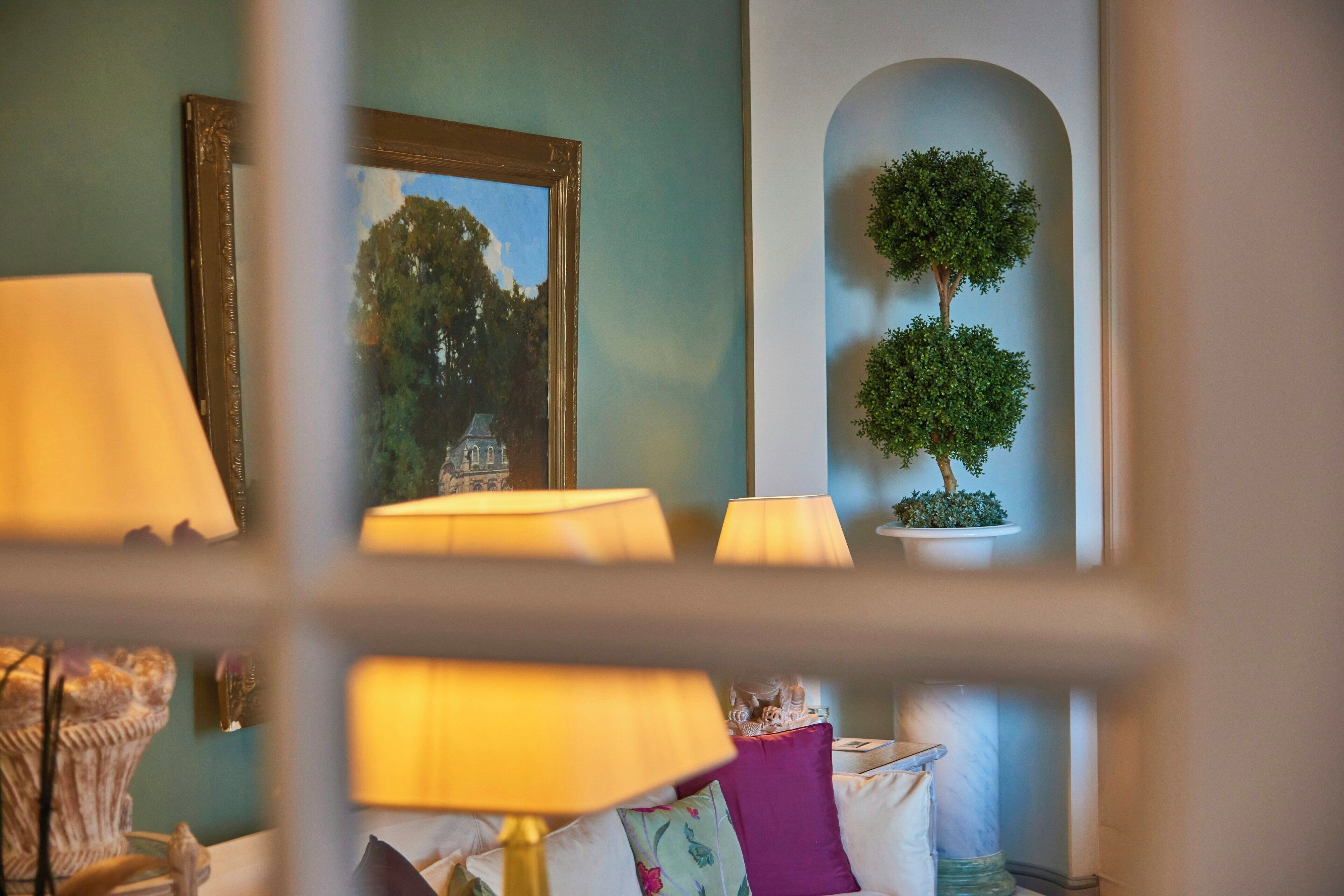 A room with a lamp, a framed picture, and a potted plant.
