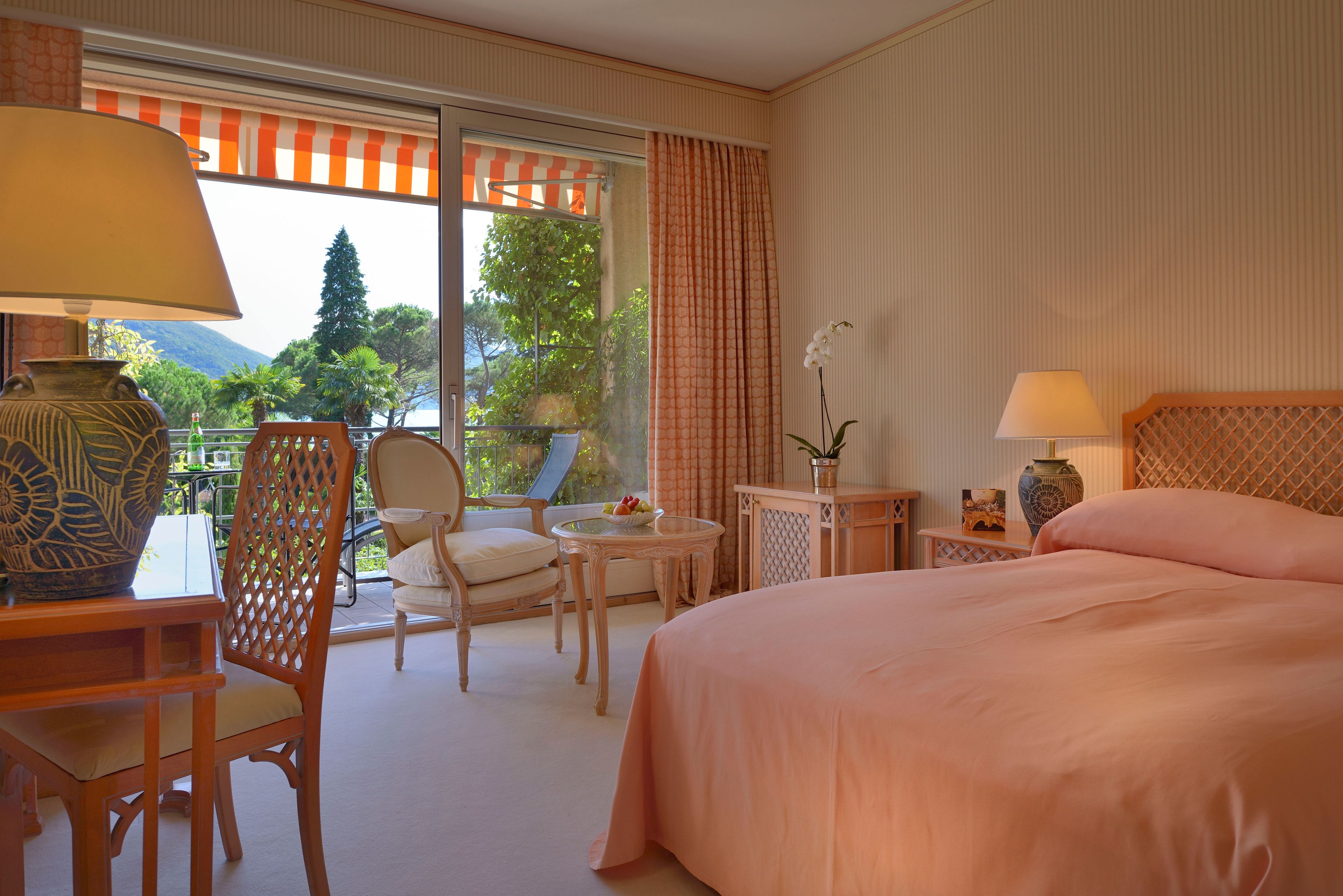 Une chambre d’hôtel avec un grand lit, une chaise, une petite table et une vue sur l’extérieur.