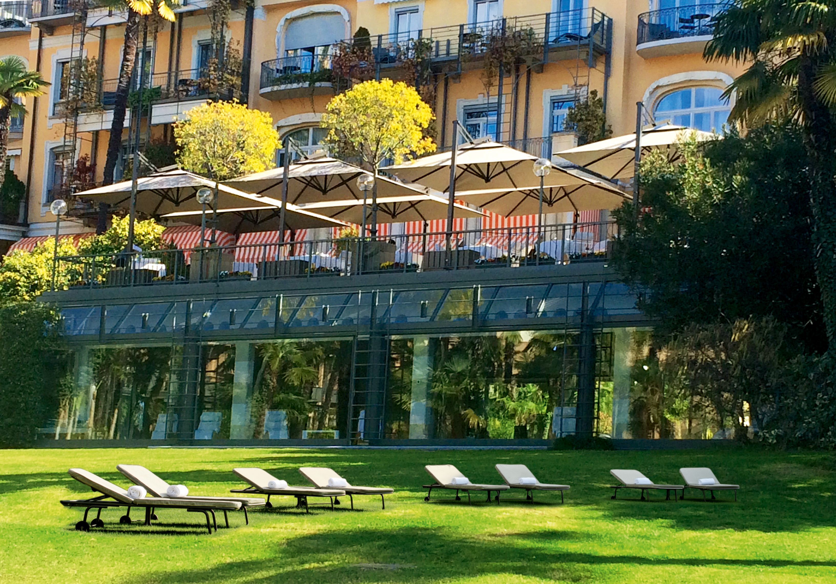 A hotel with outdoor seating, a glass bridge, and a pool area.