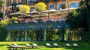 A hotel with outdoor seating, a glass bridge, and a pool area.