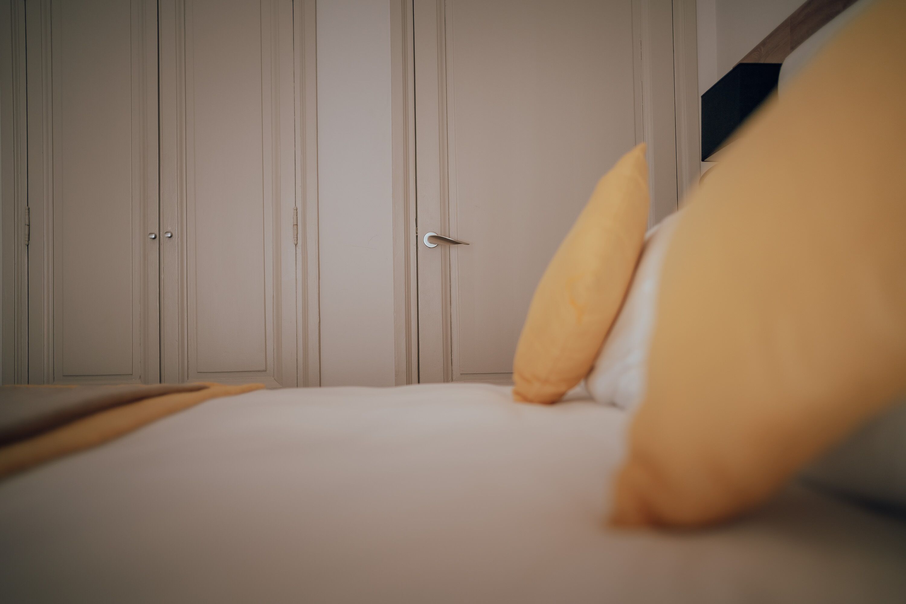 A bedroom with a bed, pillows, and a wardrobe.