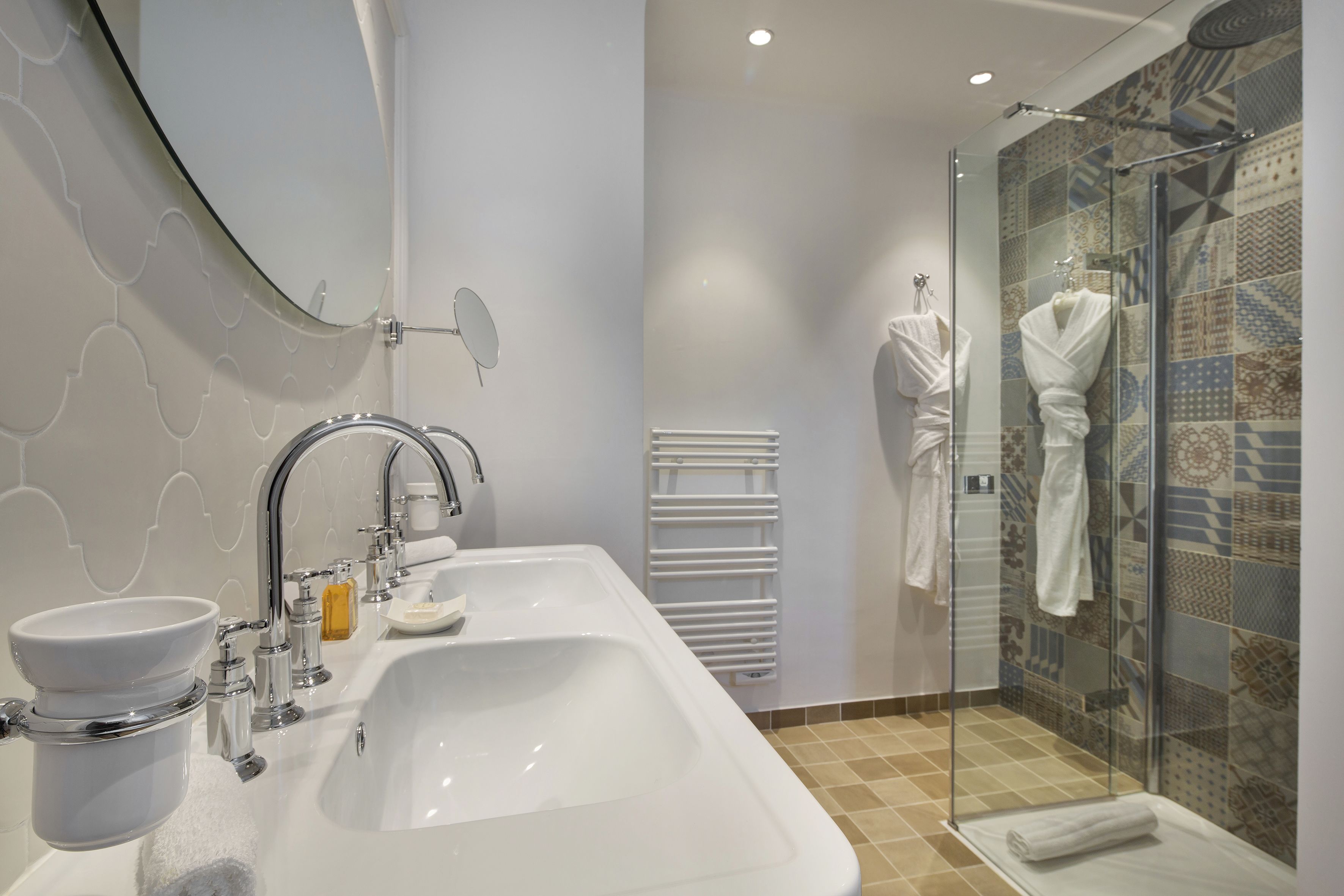 A modern bathroom with a large sink, mirror, and glass shower enclosure.