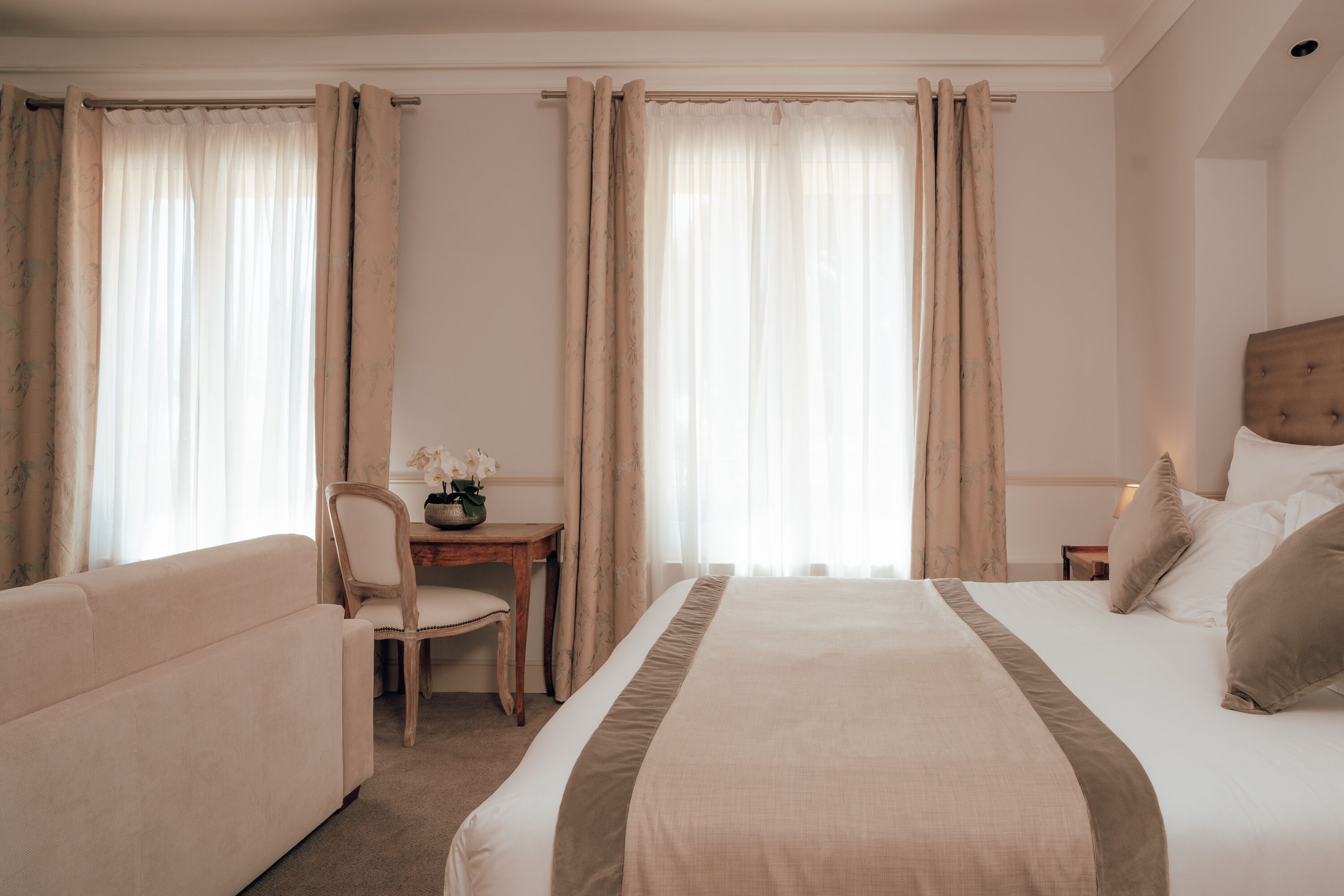 Una habitación de hotel con cama, sofá, escritorio y cortinas.
