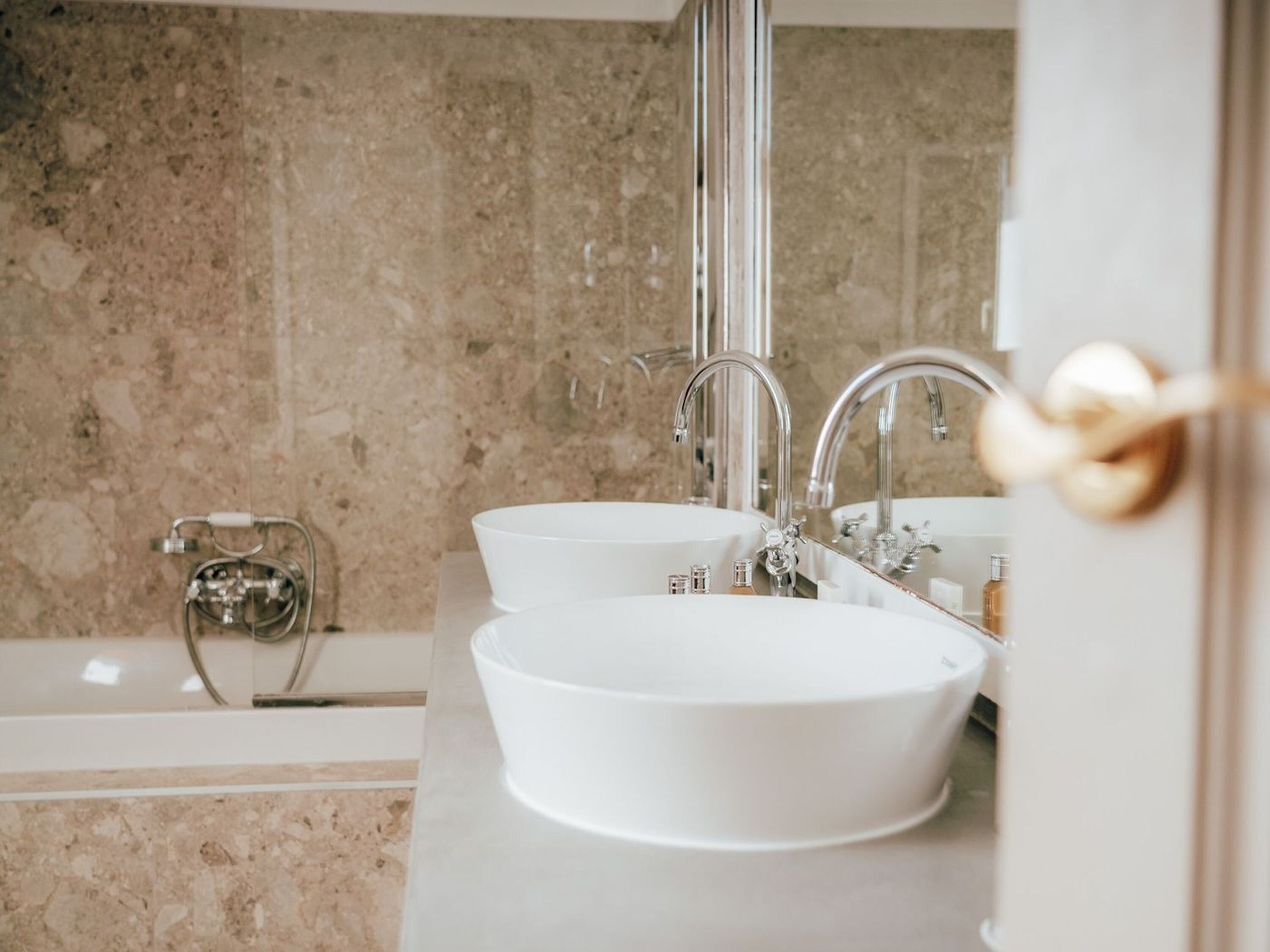 A bathroom with two white sinks, a bathtub, and a large mirror.