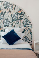 A bed with white and blue bedding, a dark blue pillow, and a floral-patterned headboard.