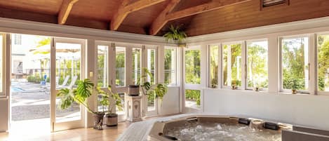 A spa area with a hot tub, large windows, and potted plants.
