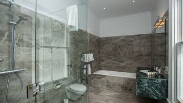 A modern bathroom with a glass-enclosed shower, a toilet, a bathtub, and a marble countertop sink.