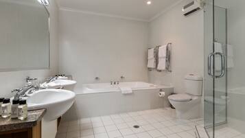 A modern bathroom with two sinks, a bathtub, a toilet, and a glass shower enclosure.