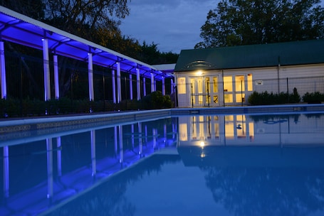 Una piscina al aire libre de temporada, sombrillas