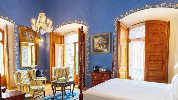 A spacious bedroom with a large bed, wooden furniture, and a chandelier. - La Casa de la Marquesa (Querétaro)