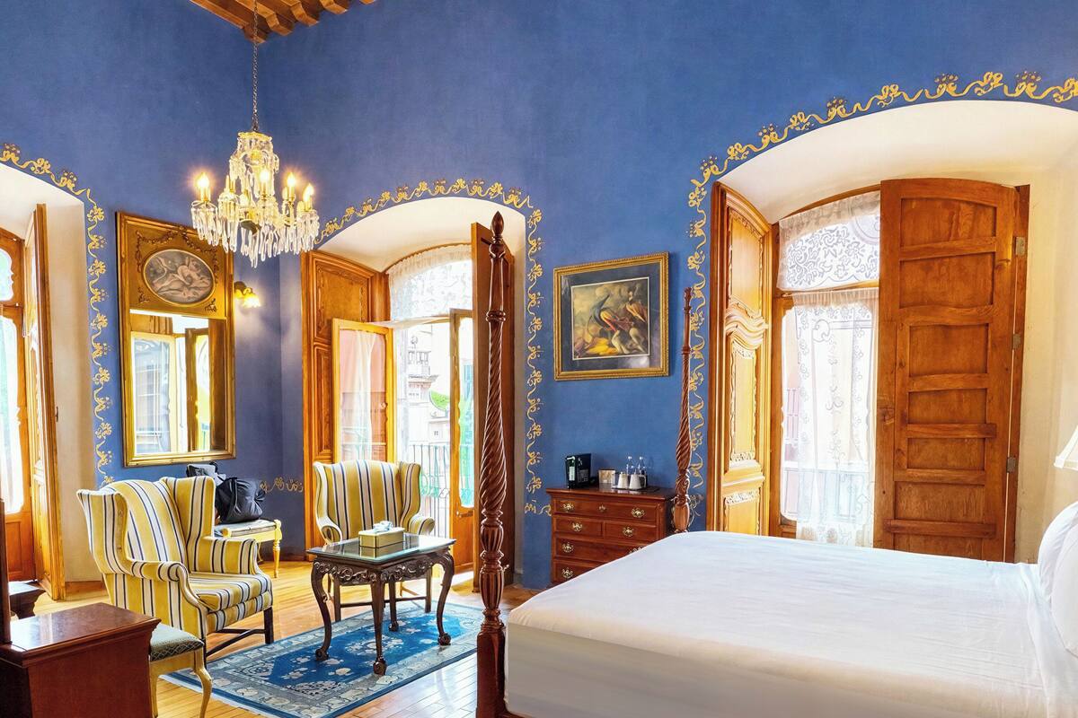Un dormitorio amplio con una cama grande, muebles de madera y un candelabro.