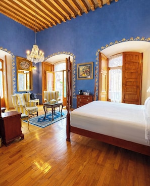 A spacious bedroom with a large bed, wooden furniture, and a chandelier.