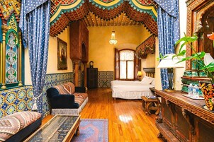 Una habitación tradicional con sofá, cama, mesa de centro de madera y una lámpara decorativa.