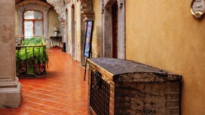 A corridor with tiled flooring, an arched doorway, and a vintage wooden chest. - La Casa de la Marquesa (Querétaro)