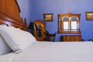 Un dormitorio con una cama de madera, un aparador, una silla, un espejo y una lámpara.