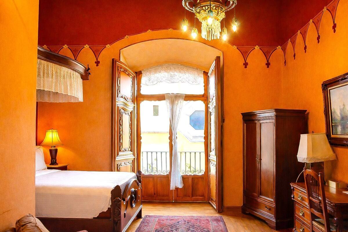 Una habitación de hotel con cama, escritorio, armario y candelabro.