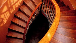 A wooden spiral staircase with a handrail and a potted plant on the landing. - La Casa de la Marquesa (Querétaro)
