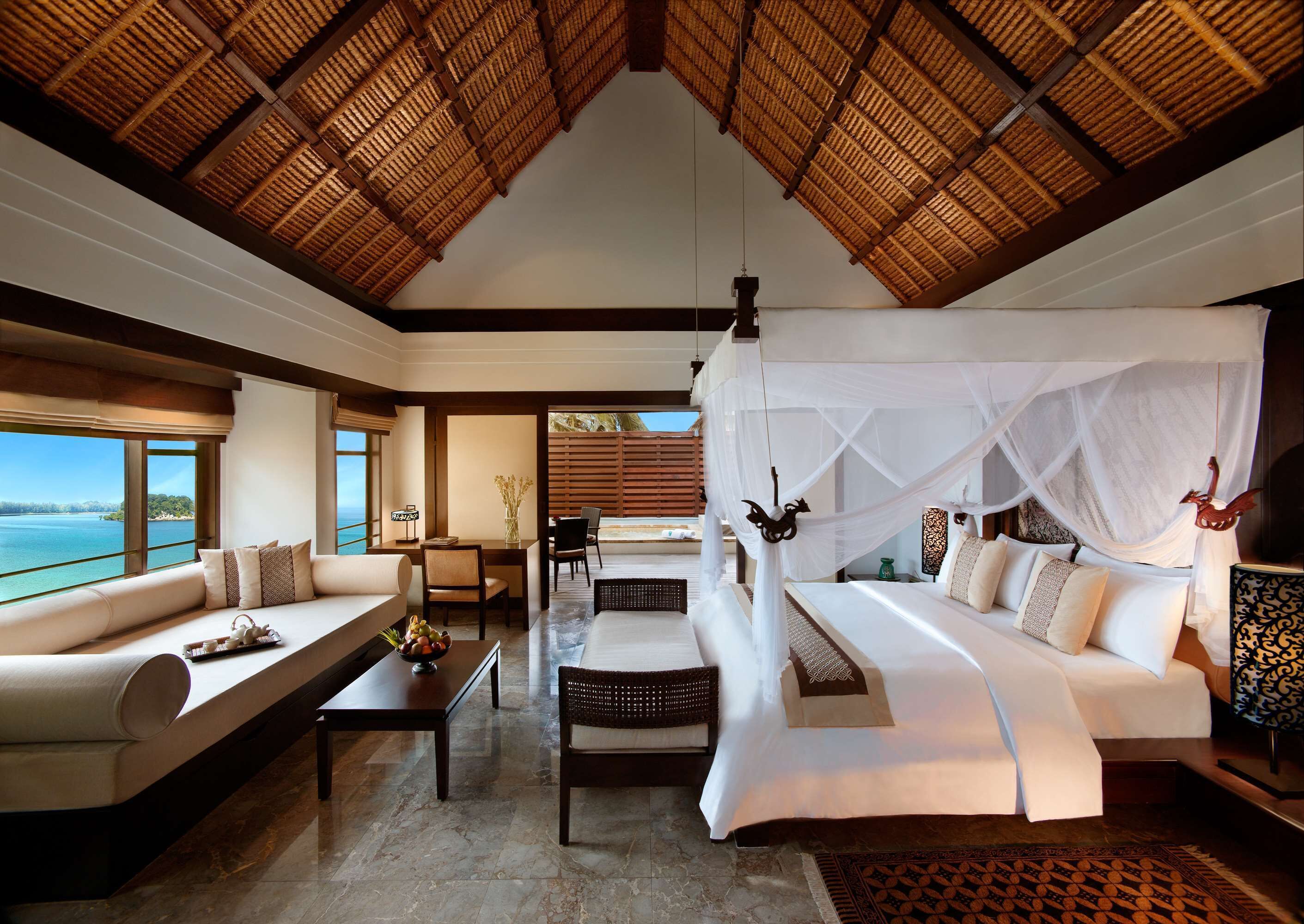A spacious room with a large bed, a sofa, and a dining area, featuring a view of the sea.