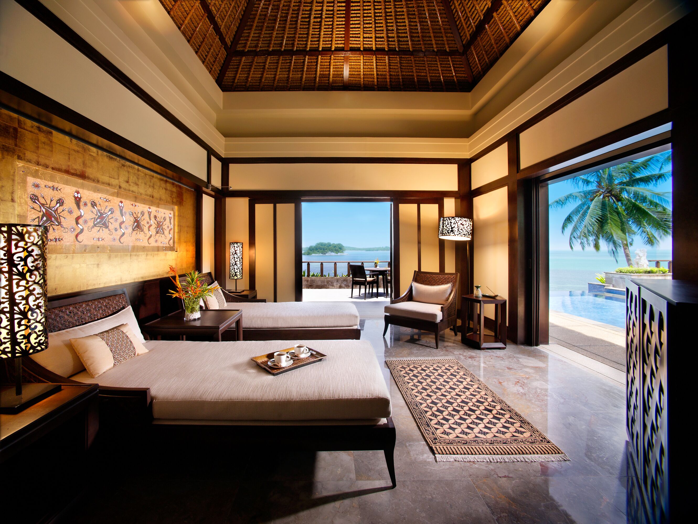 Quarto espaçoso com uma cama grande, uma cama menor e um espaço de estar com vista para o oceano.