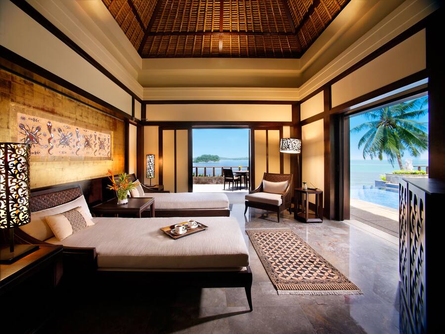 Quarto espaçoso com uma cama grande, uma cama menor e um espaço de estar com vista para o oceano.