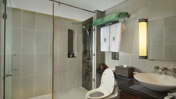 A modern bathroom with a glass-enclosed shower, a white toilet, and a sink with a mirror above it.