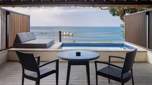 Un balcon avec vue sur la mer, une petite piscine et des sièges.