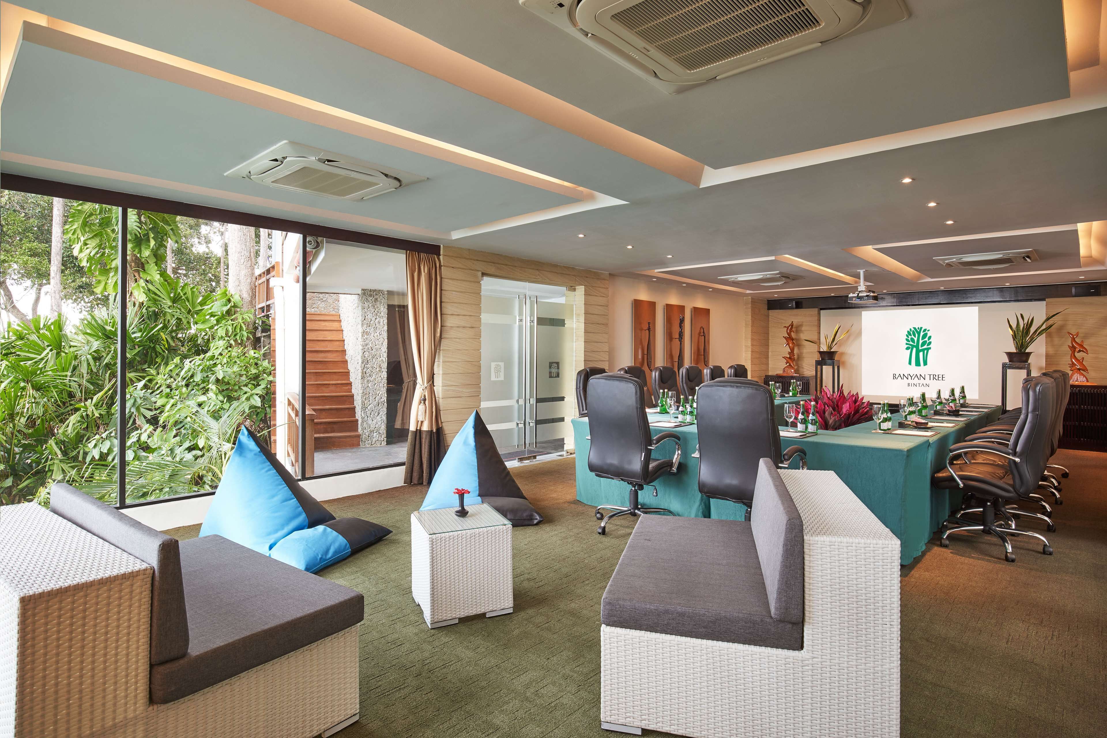A conference room with a long table, chairs, and a presentation screen.