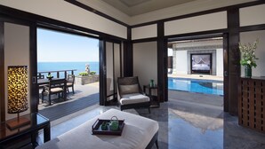 Un balcón amplio con vistas al mar, una piscina y un área de estar cómoda con mesa y sillas.