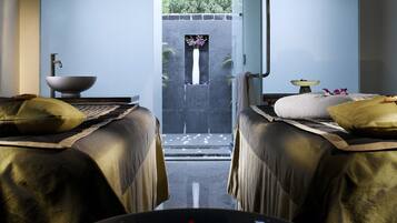 Experience serenity in this spa room, featuring two massage tables and a peaceful outdoor area with a tranquil view.