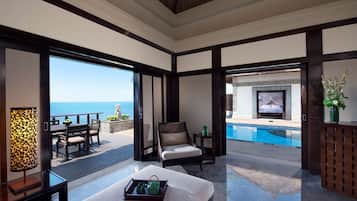 Amplia habitación con un gran ventanal con vistas a una piscina y al mar.
